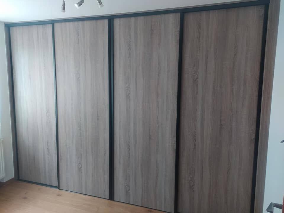 Vierteiliger graubrauner Schrank mit dunklen Türprofilen