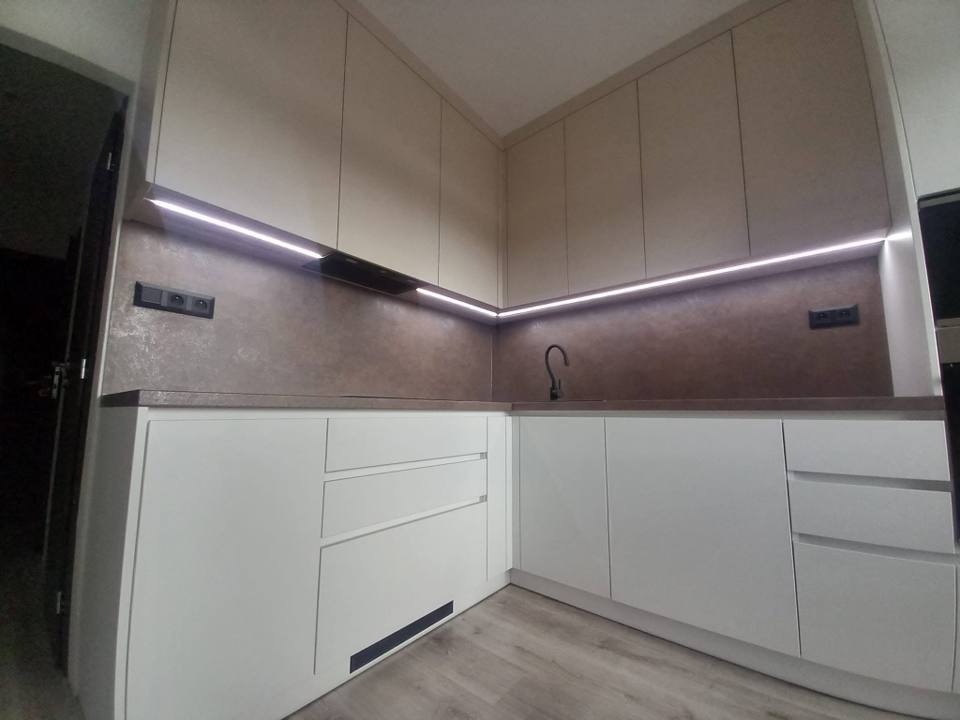Helle Eckküche mit brauner Steinrückwand und LED-Band