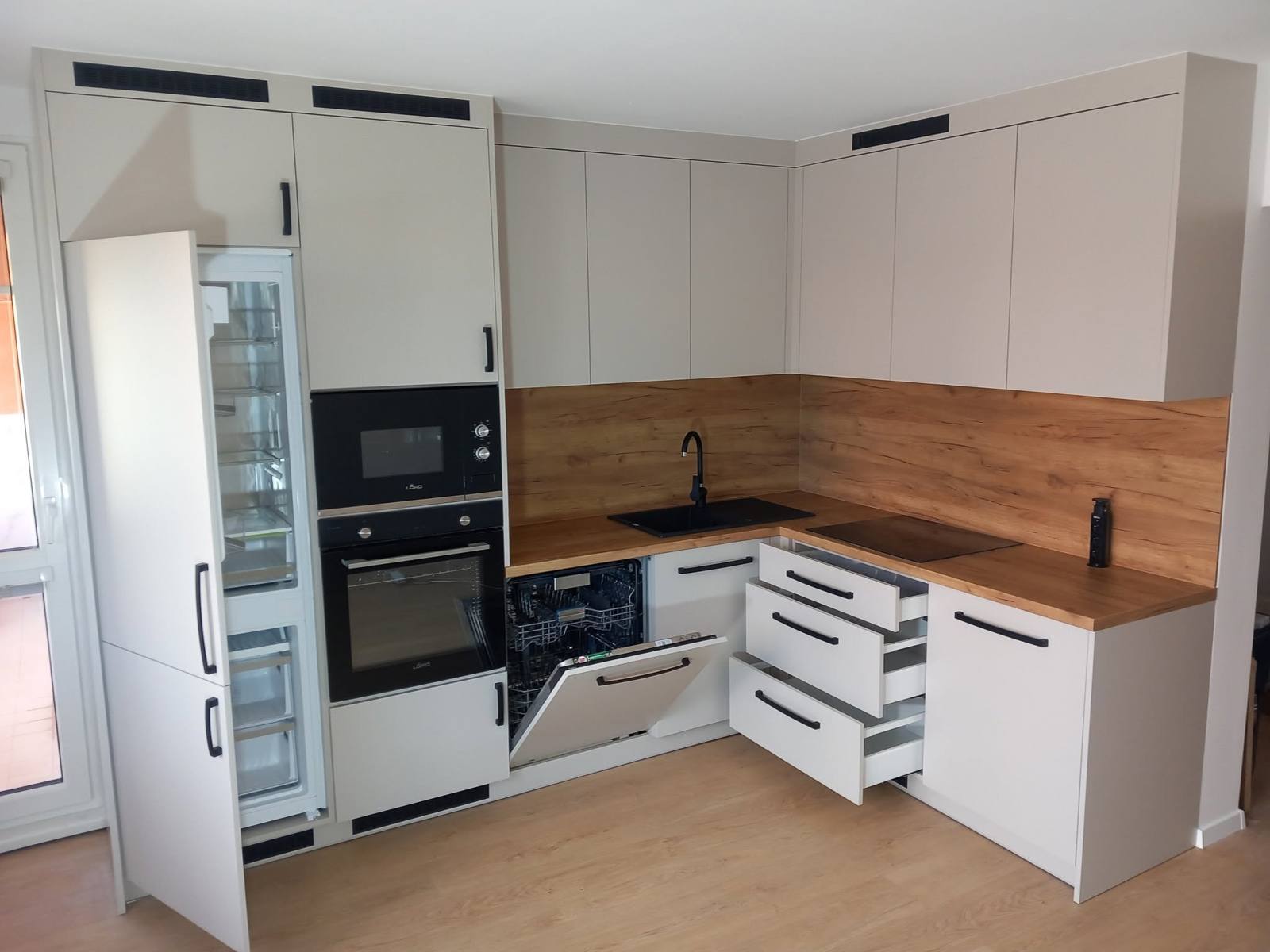 Geöffneter Einbaukühlschrank, Geschirrspüler und ausgezogene Laden