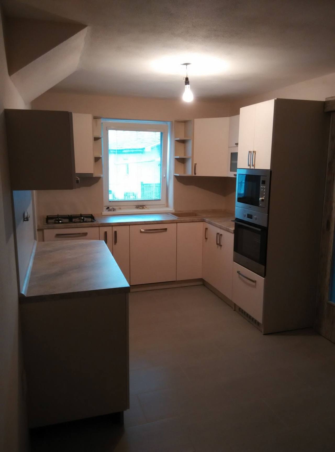 Halbinsel mit heller Platte und Hochschrank mit Einbaugeräten