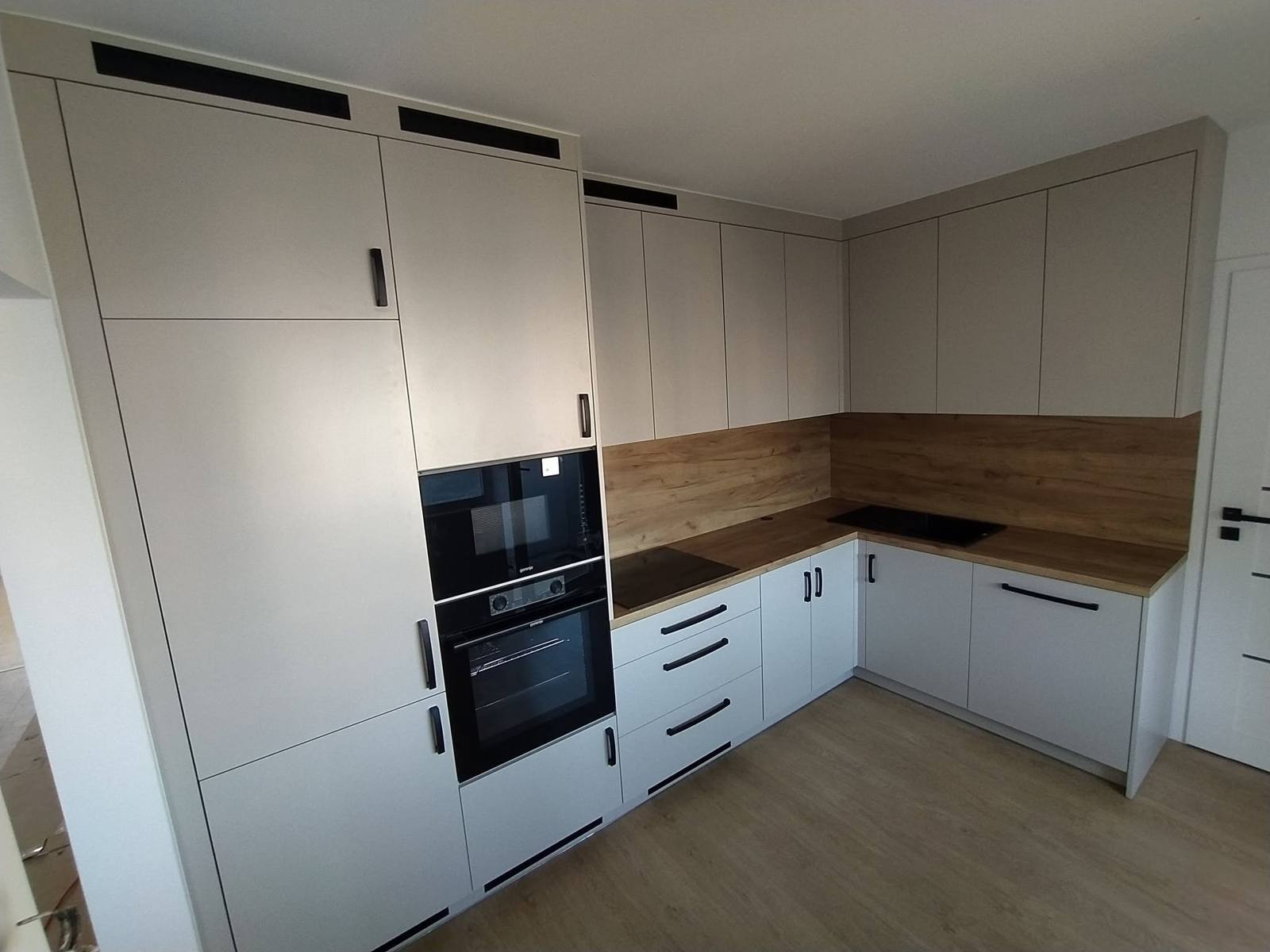 Helle Küche mit Eichendekor und hohem Schrank mit Backrohr