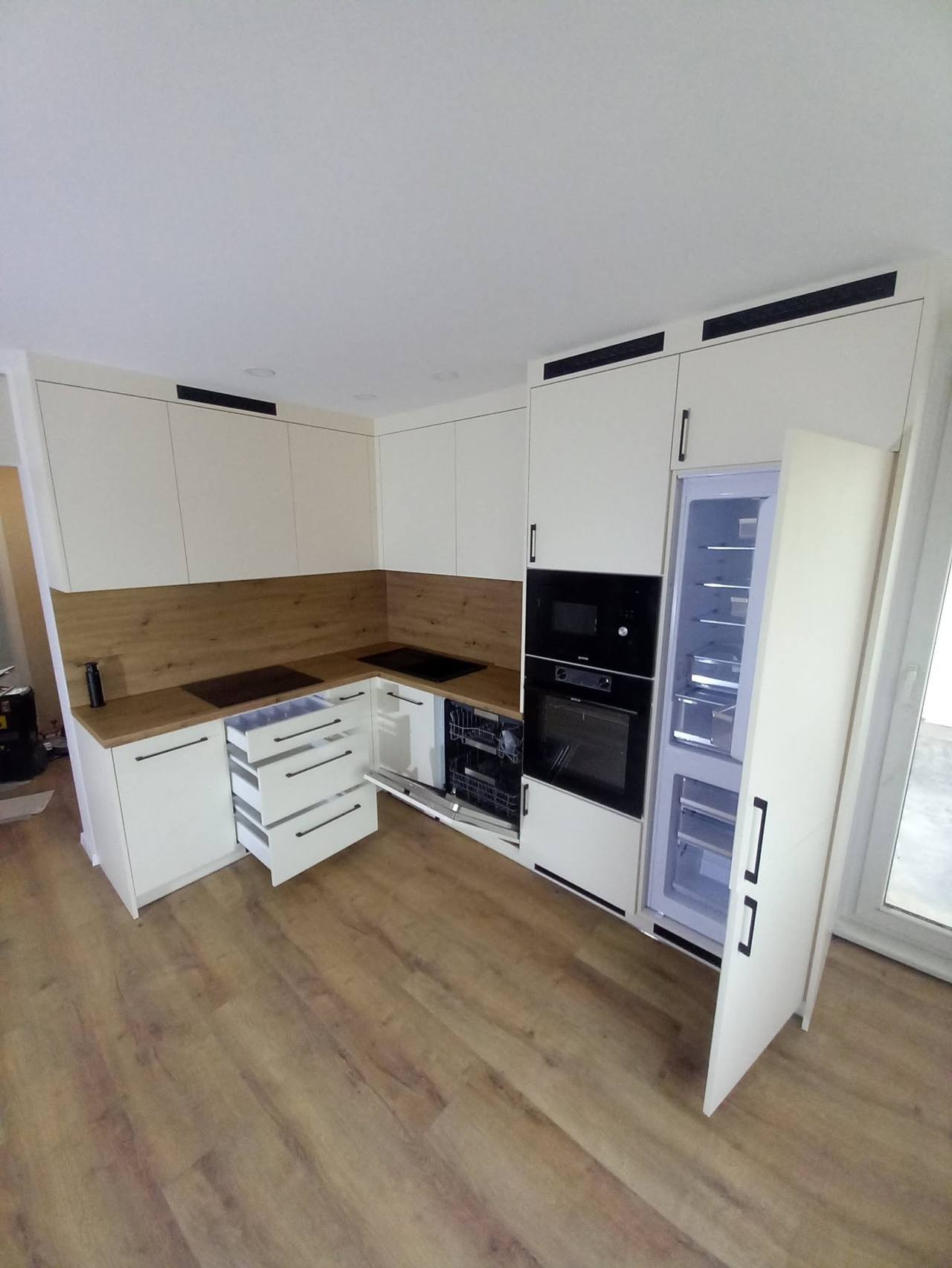 Helle Küche mit geöffnetem verkleidetem Einbaukühlschrank