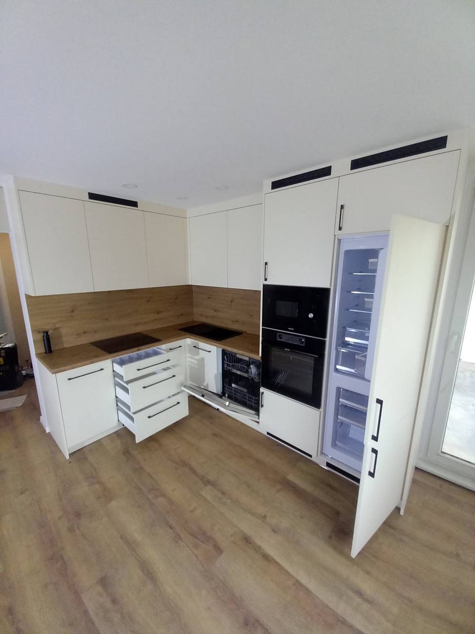 Helle Küche mit geöffnetem verkleidetem Einbaukühlschrank