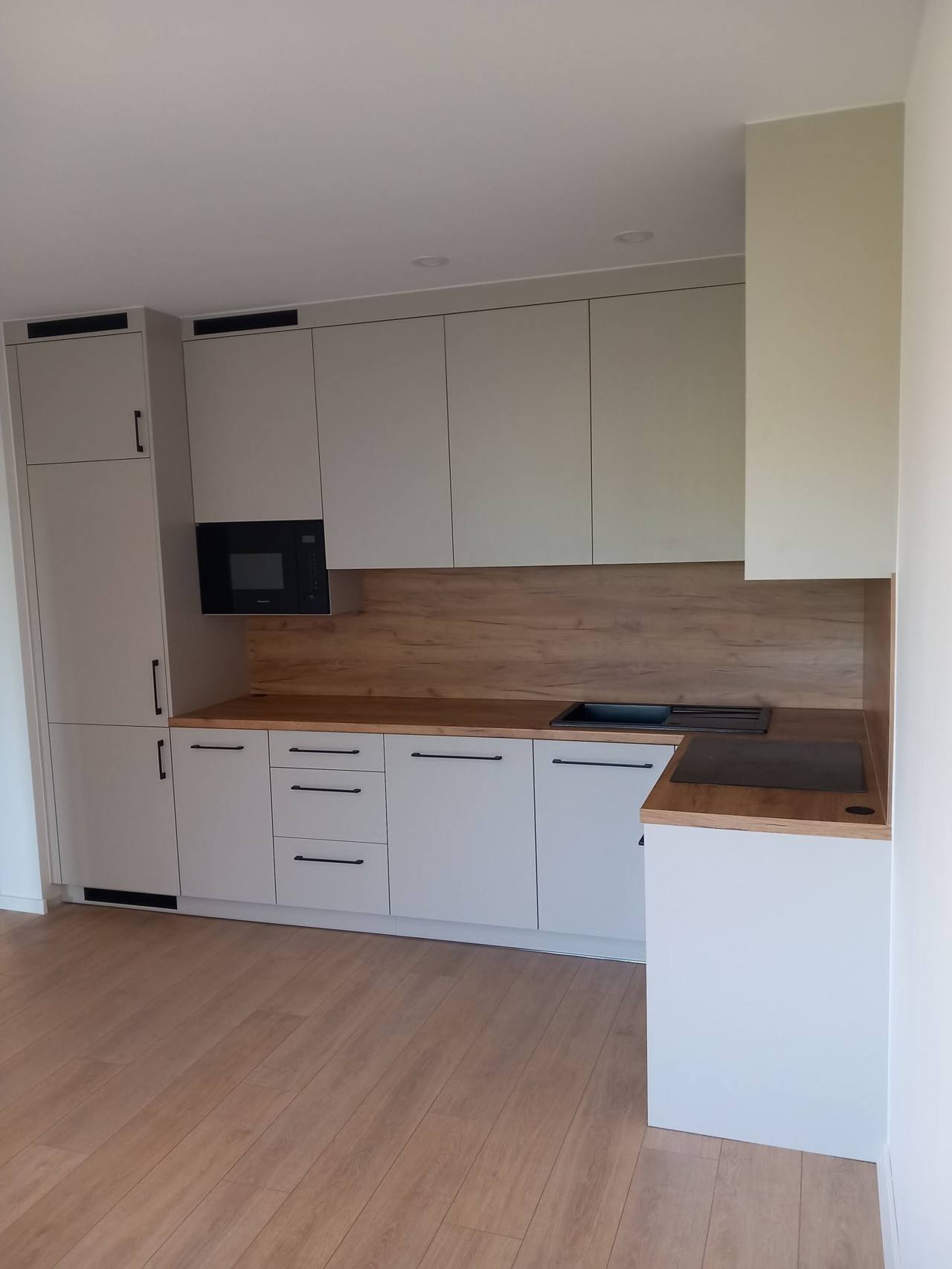 Helle Küche mit hohem Schrank und kurzer Halbinsel