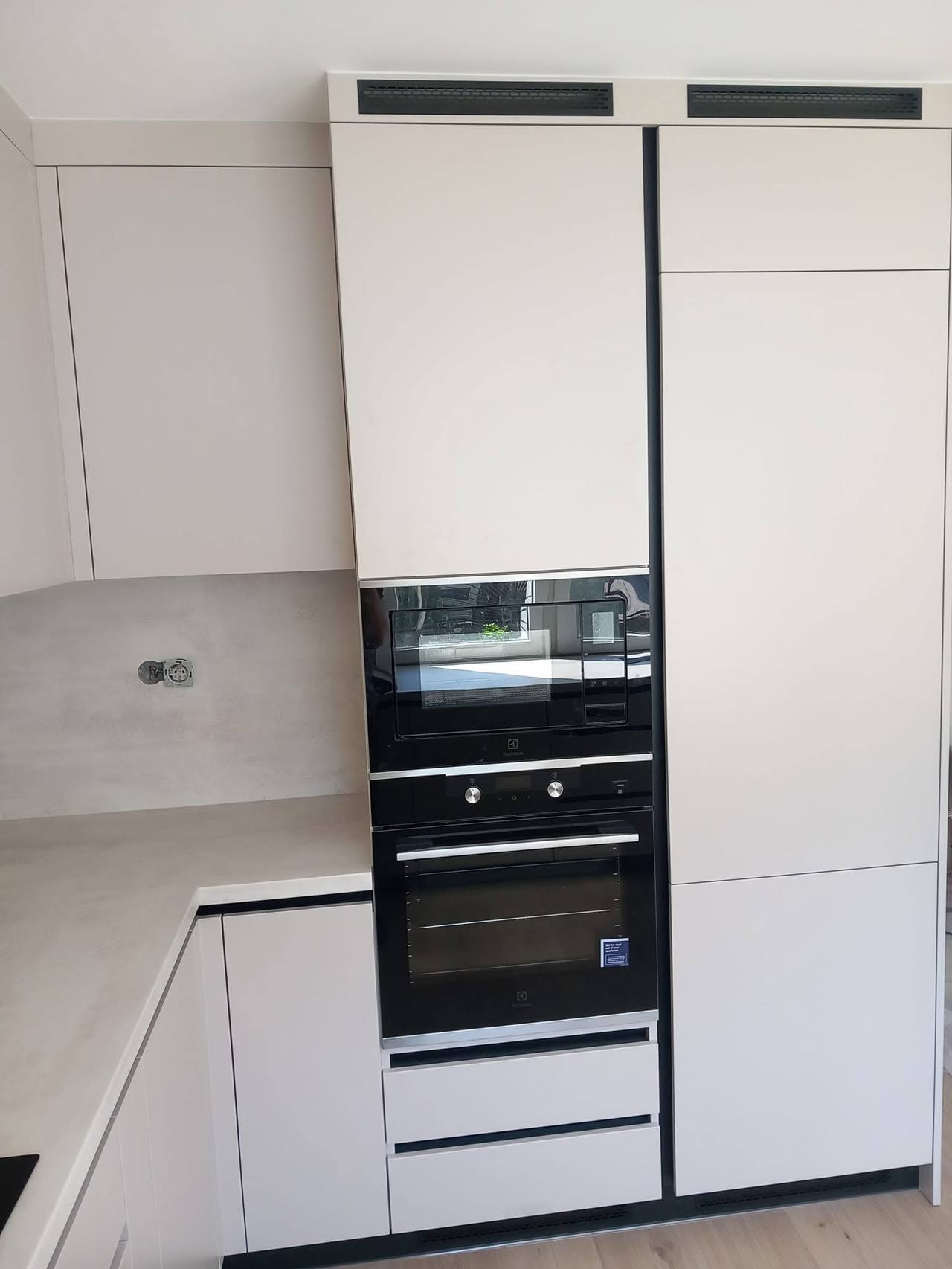 Helle Hochkästen mit schwarzem Backrohr, Mikrowelle und Kühlschrank