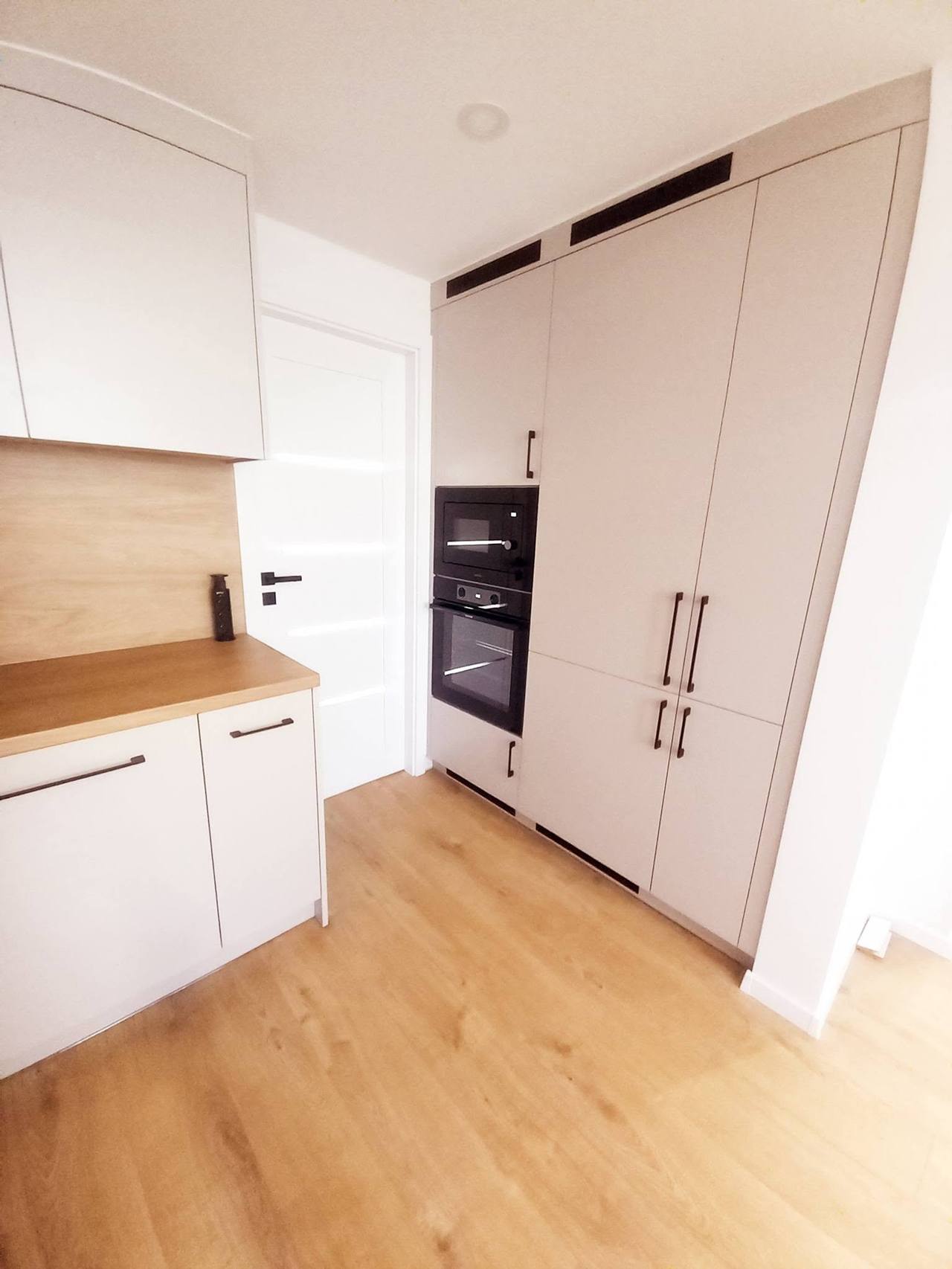 Helle Küche mit hohen Schränken am Eingang der Wohnung