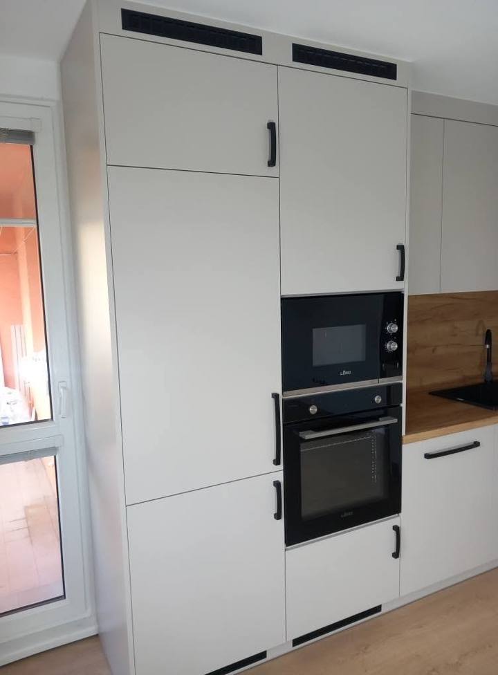 Helle hohe Küchenschränke mit schwarzem Backrohr und Mikrowelle.