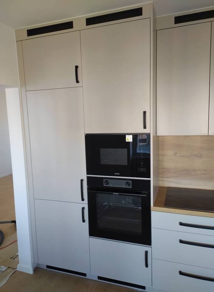 Hochschrank in Kaschmirton mit Einbaugeräten und schwarzen Griffen.