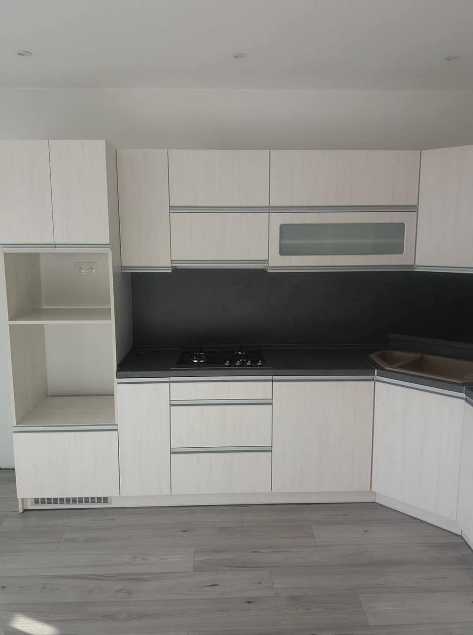 Helle Eckküche mit anthrazitfarbener Rückwand und Hochkasten mit Nische