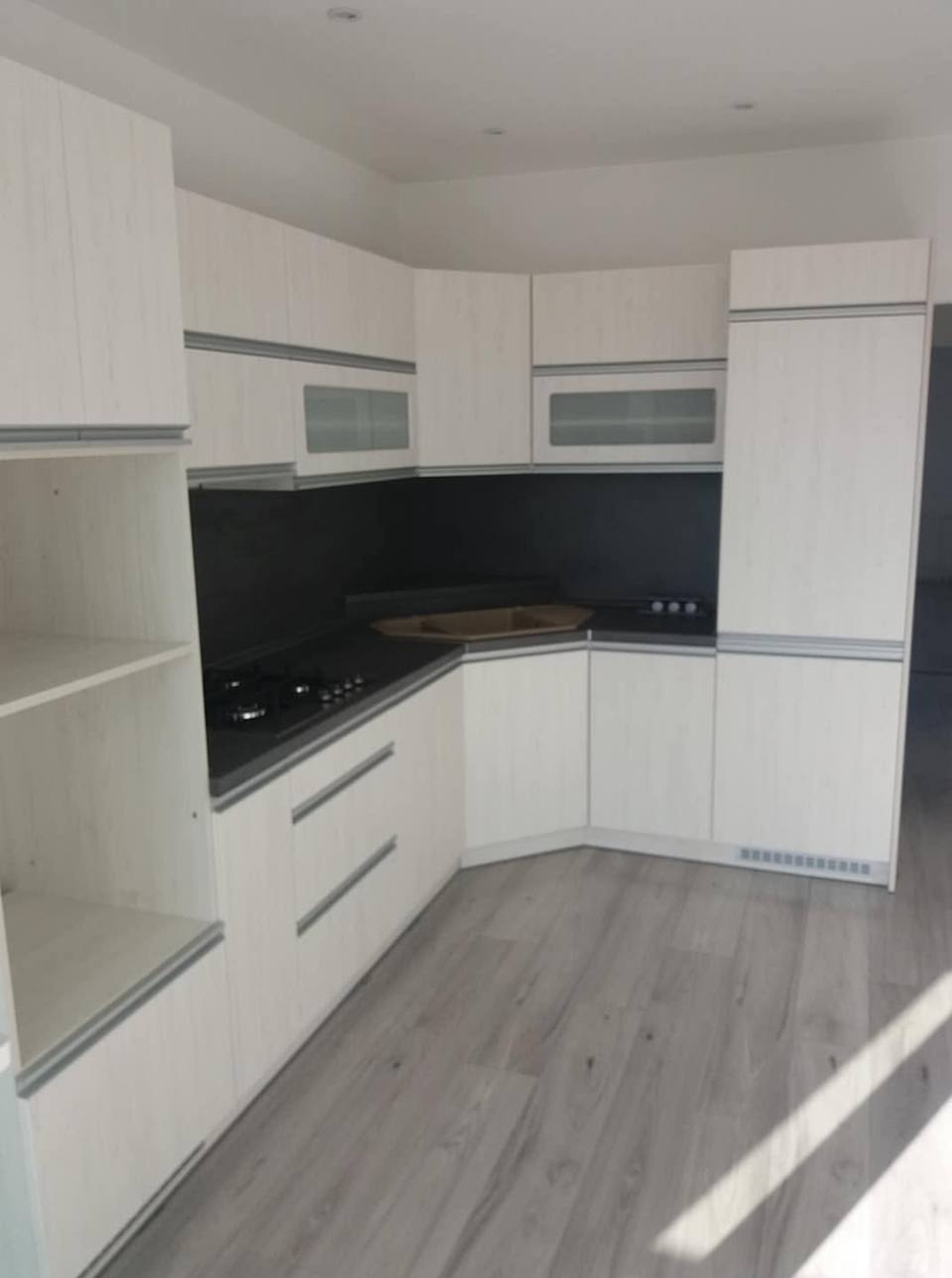 Blick in die Küchenecke mit dunkler Platte und offenen Fächern