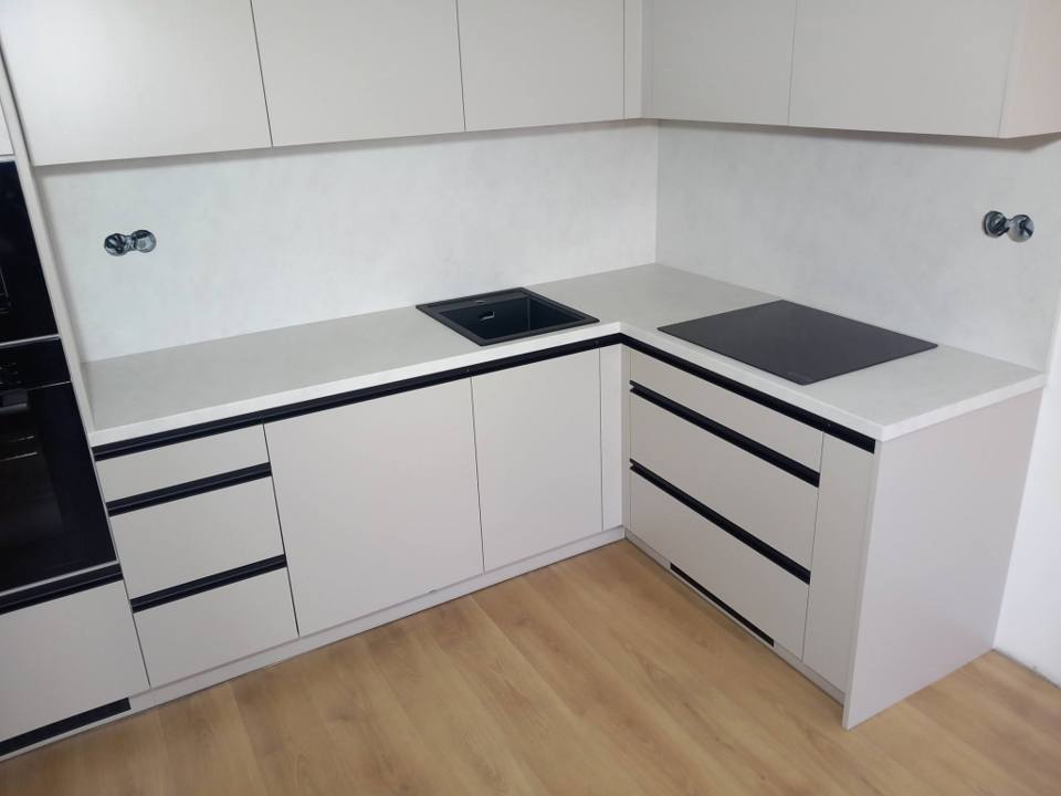 Eckzeile mit schwarzer Abwasch, Kochfeld und schwarzen Griffprofilen
