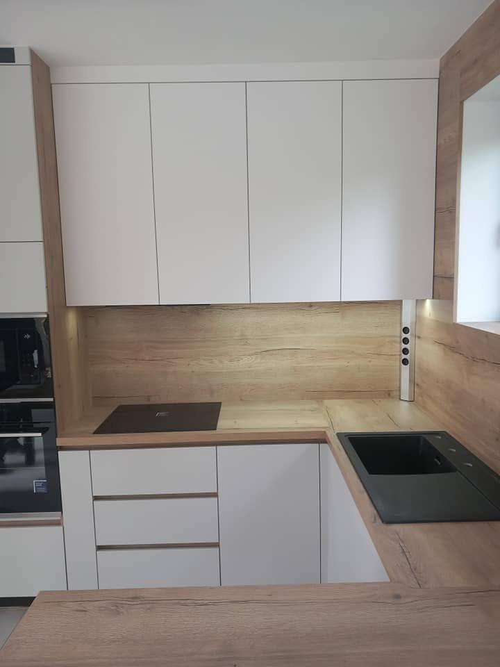 Helle Eckküche mit Eichendekor-Rückwand und Induktionsfeld