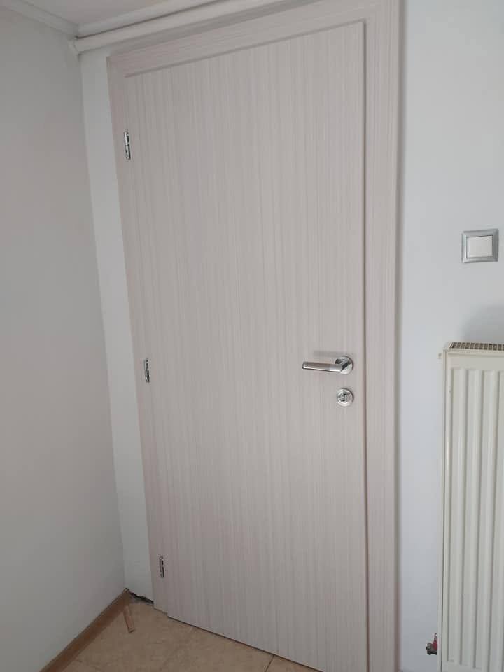 Helle Innentür in gebleichter Eiche beim Heizkörper auf Fliesen.