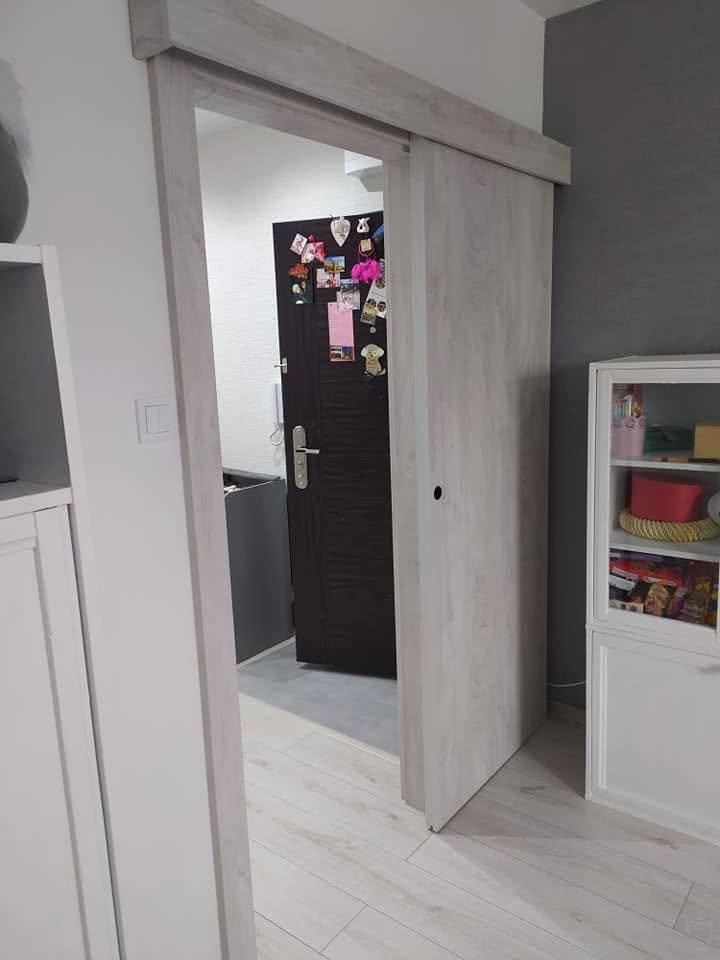 Hellgraue Tür an der Wand mit dekorativem Regal und Blumen