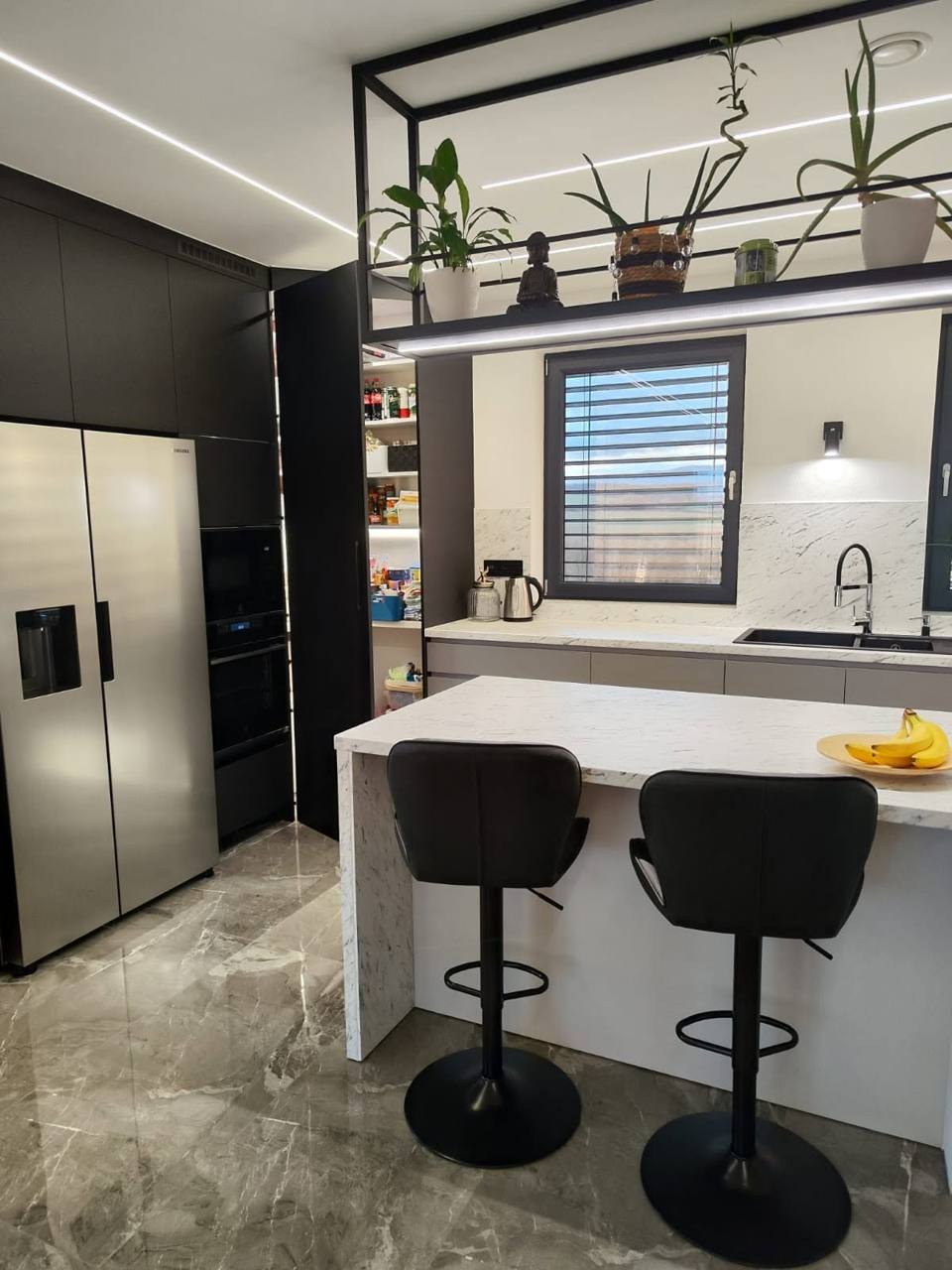 Dunkle Küche mit Side-by-Side-Kühlschrank und Bartheke in Marmoroptik