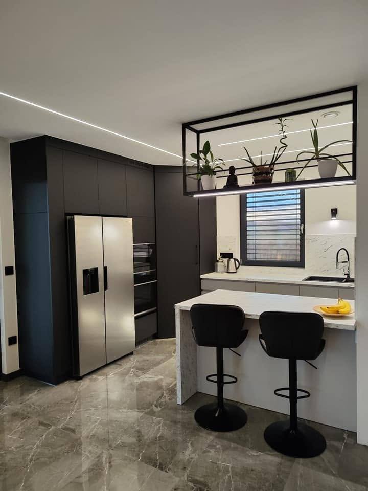 Schwarze Hochkästen mit Kühlschrank und Insel mit Barhockern