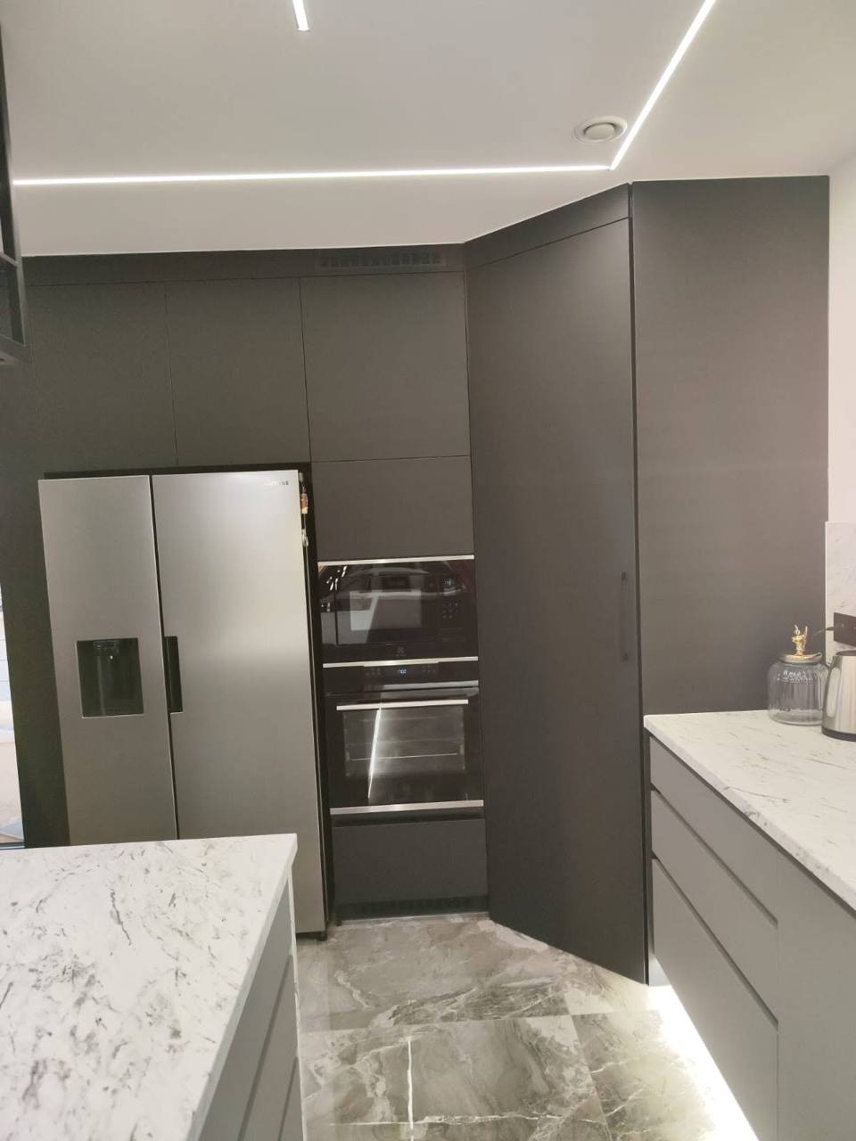 Schwarze Eck-Hochkastenwand mit Edelstahl-Kühlschrank und Backrohren