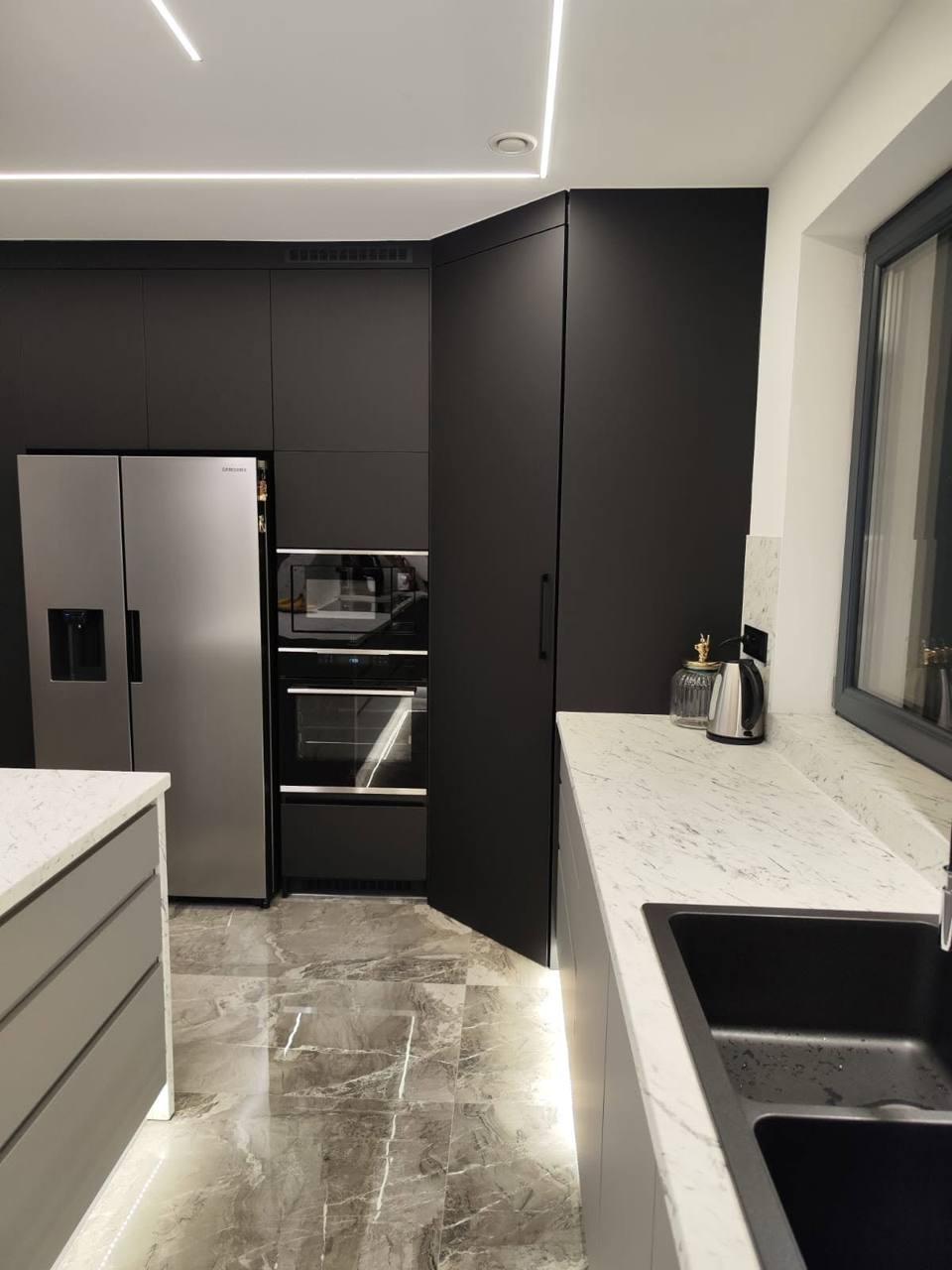 Schwarze Hochkästen mit Kühlschrank und beleuchteter Sockel der Zeile