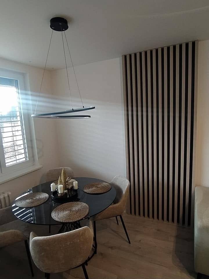 Dunkle senkrechte Lamellen an der Wand neben dem runden Tisch