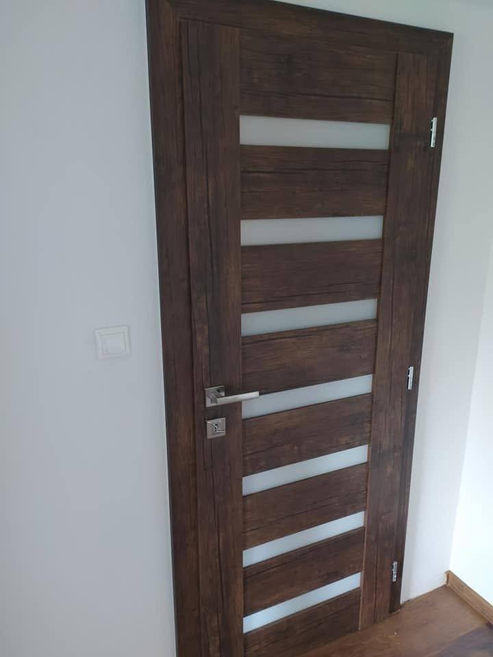 Detail der dunklen Tür mit waagrechten Glasstreifen und Edelstahlklinke