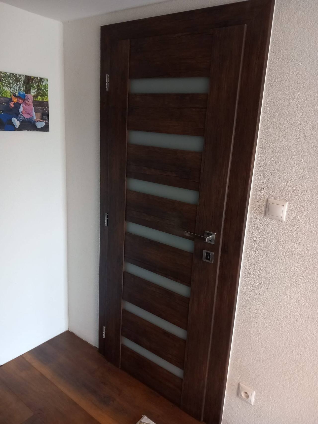 Dunkle Eichentür mit waagrechten Glasstreifen im Zimmer mit dunklem Boden