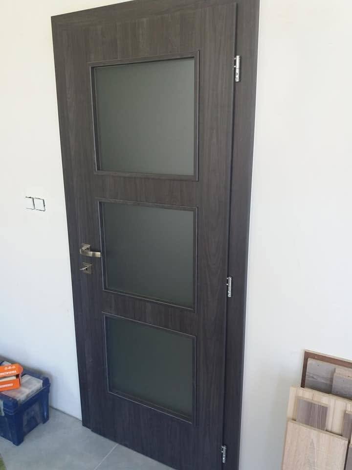 Dunkle Tür in Wenge-Dekor mit drei quadratischen Glasfeldern bei der Stiege.
