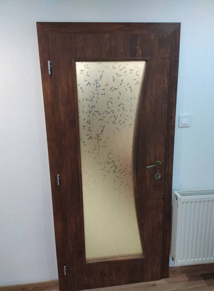 Dunkle Nussbaumtür mit geschwungenem Ornamentglas