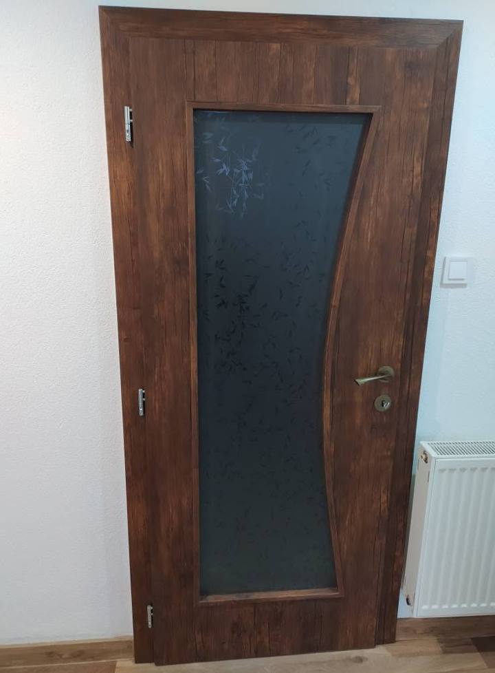 Dunkle Nussbaumtür mit geschwungenem dunklem Ornamentglas