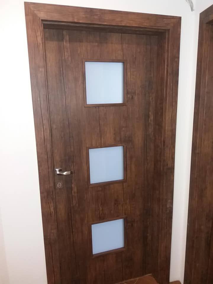 Dunkle Tür mit drei quadratischen Milchglasfeldern und Türstock