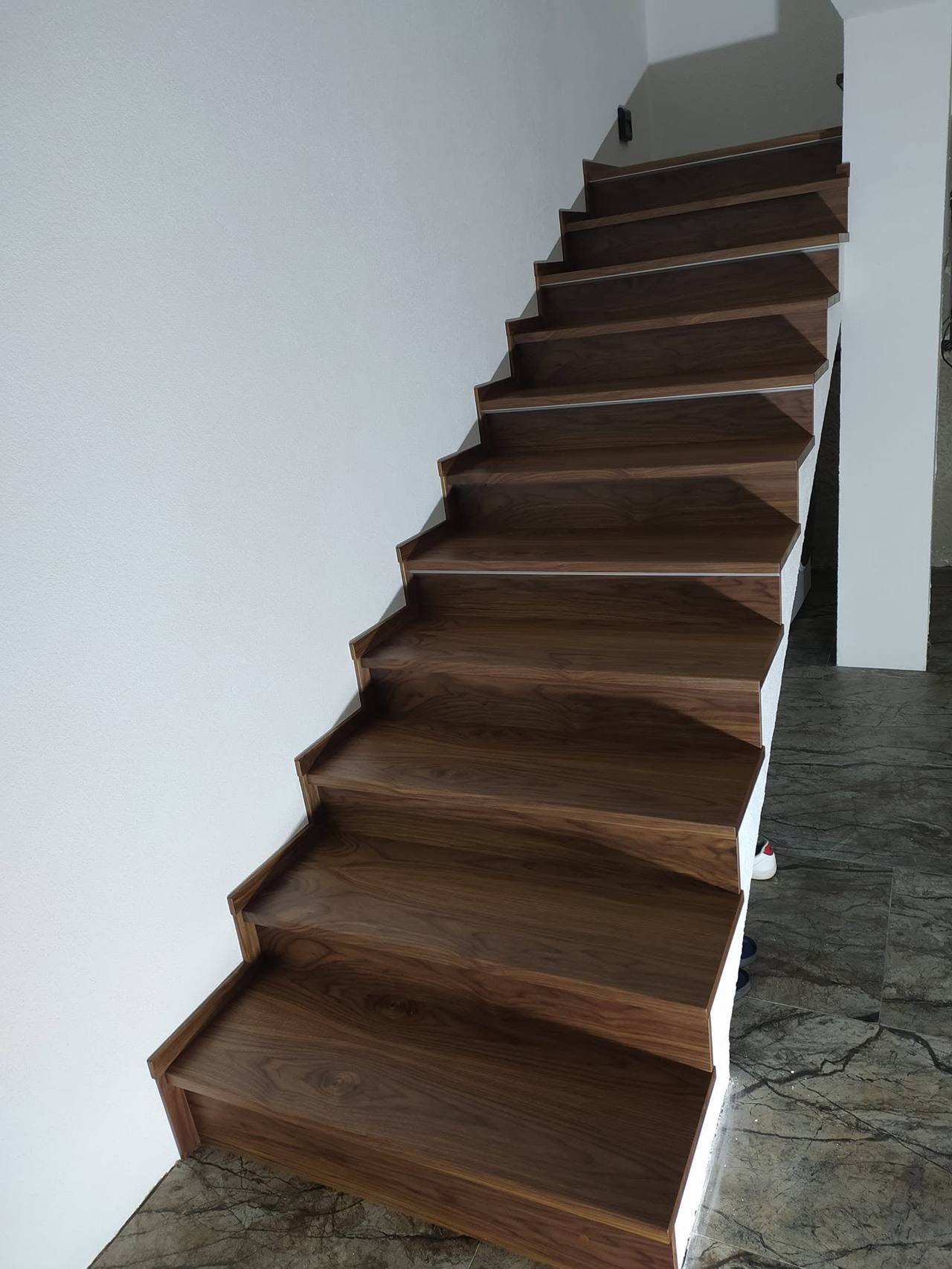Lange gerade Eichenstiege in Dunkel an weißer Wand