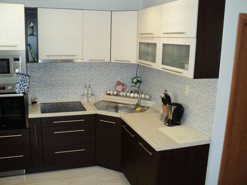Dunkelbraune Eckküche mit weißen Schränken und Mosaikfliesen
