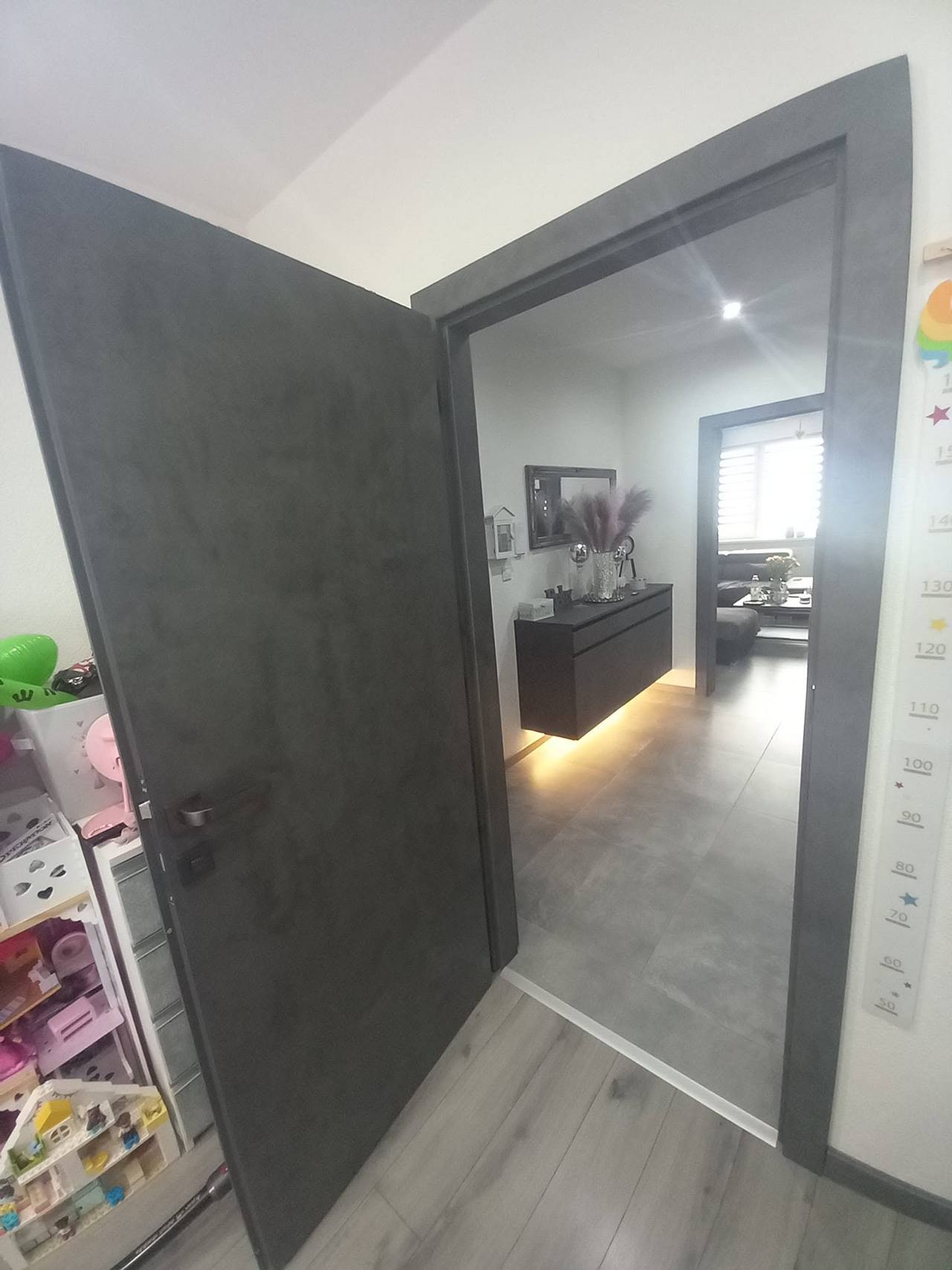 Dunkelgraue Tür mit Blick auf den Flur mit Kinderspielzeug