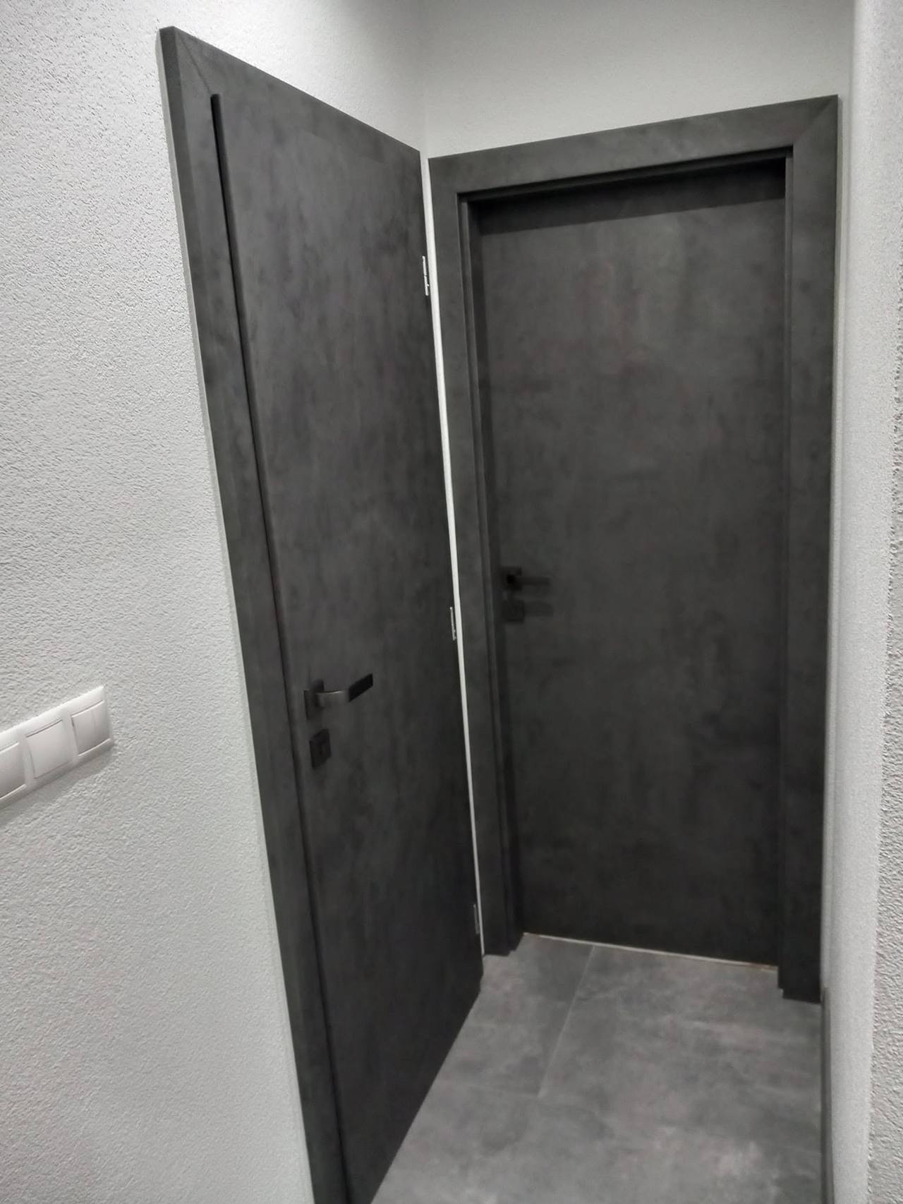 Dunkelgraue Tür aus seitlichem Blickwinkel im schmalen Flur