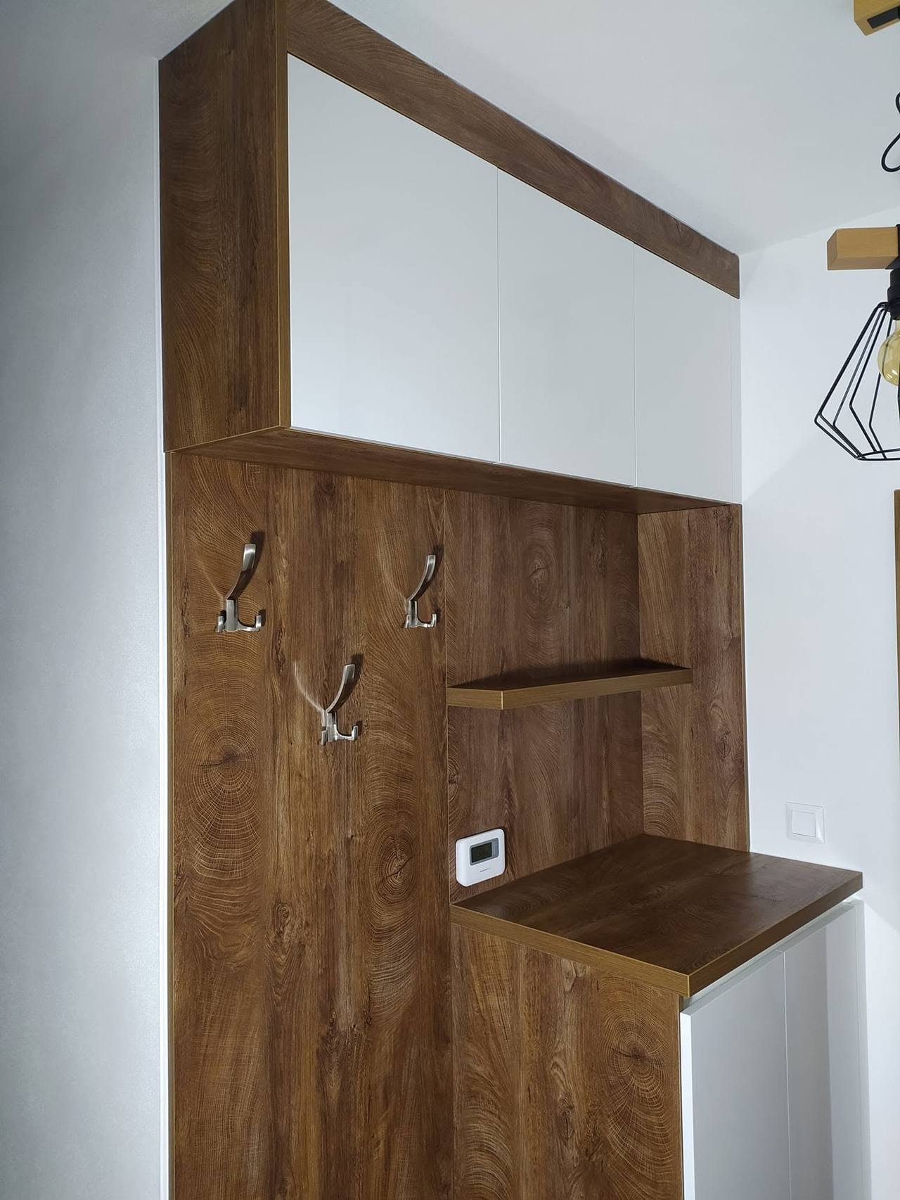 Panel s háčikmi a policou pod bielymi hornými skrinkami