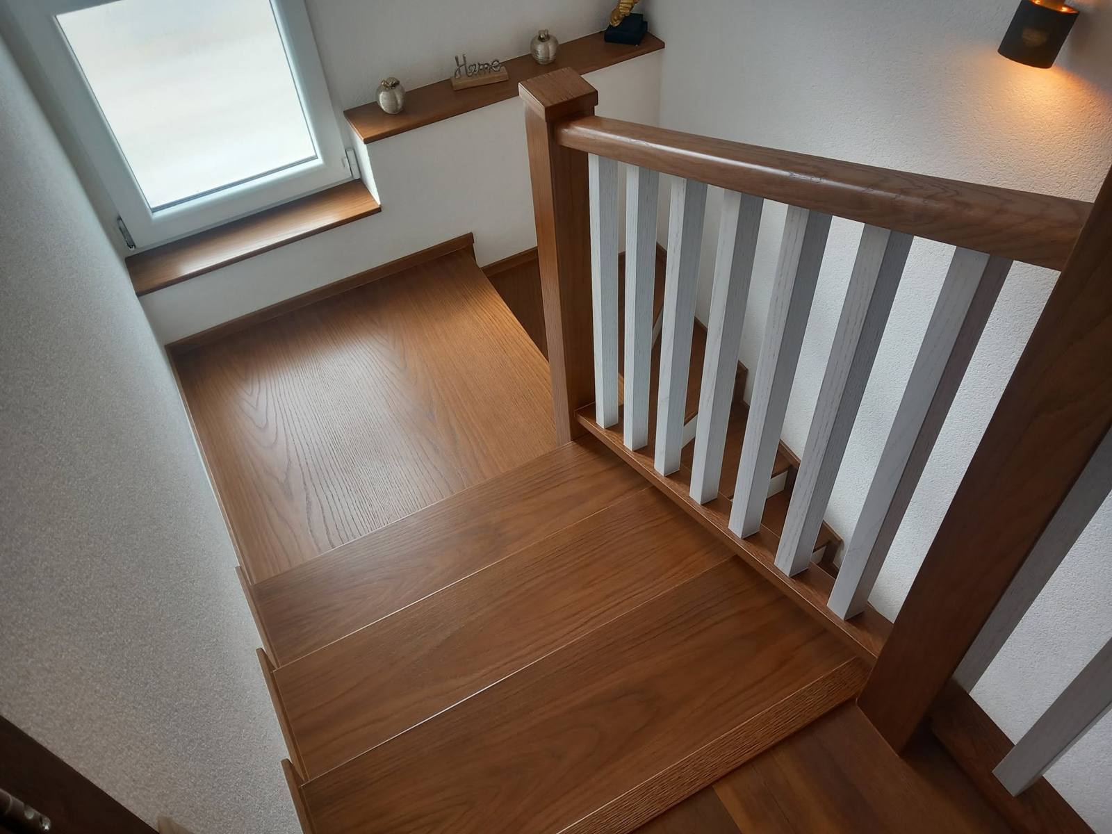 Dubové schody so zábradlím s bielymi stĺpikmi pod strešným oknom