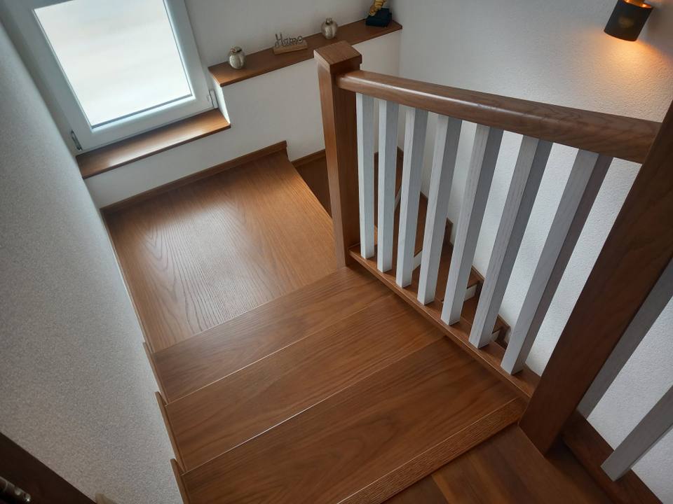Eichenstiege mit weißem Stabgeländer unter dem Dachfenster