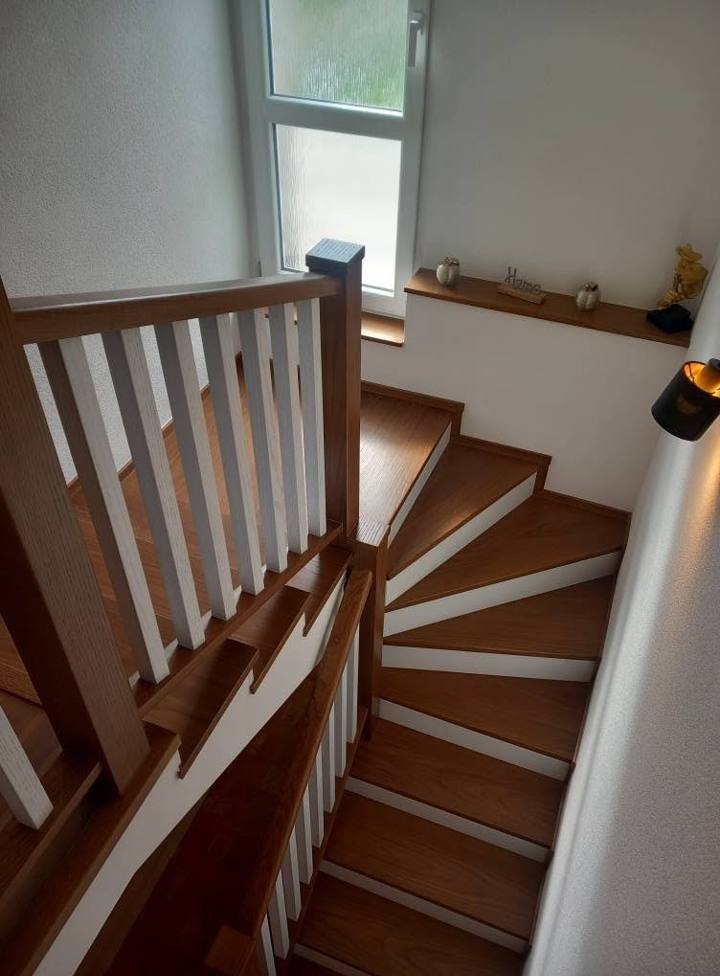 Točité schodisko s bielymi stĺpikmi zábradlia a dubovým madlom