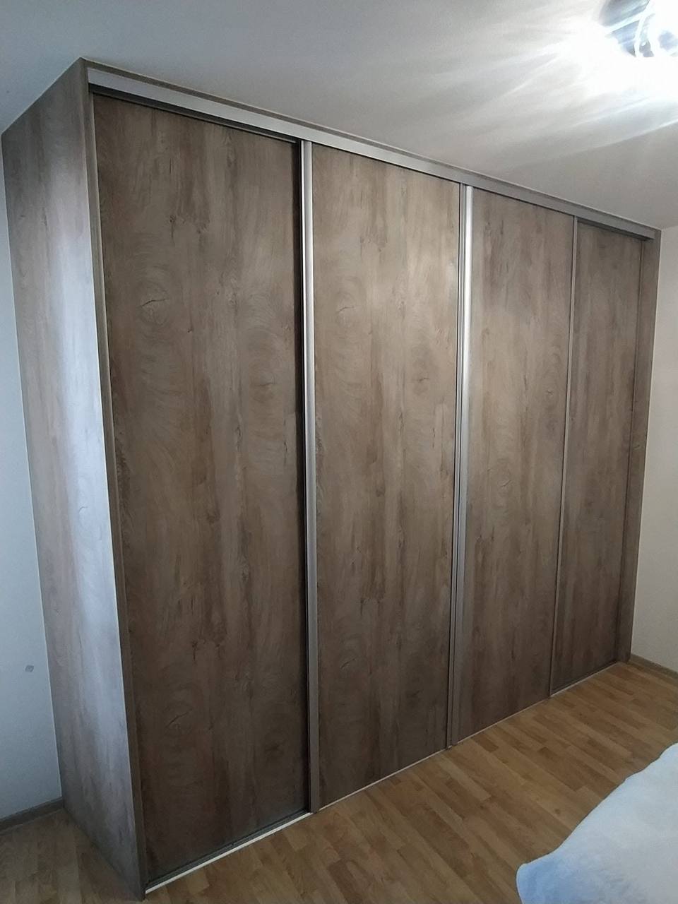 Dreiteiliger Schiebekasten in graubraunem Eichendekor neben dem Bett