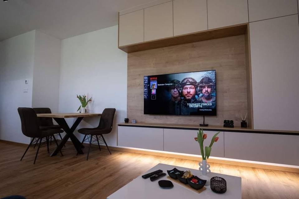 TV-Wand mit Paneel in Eichenoptik und hellen Kästen beim Essplatz