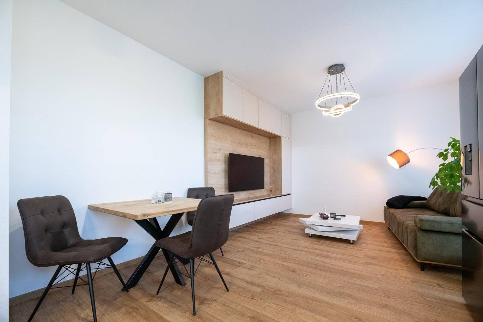 Wohnraum mit TV-Wand, Esstisch und Sofa