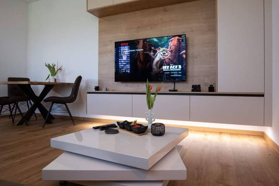 TV-Wand mit Licht unter dem Lowboard und weißem Couchtisch