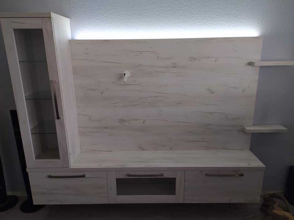 TV-Wand in hellem Dekor mit Vitrine und LED-Licht über der Rückwand