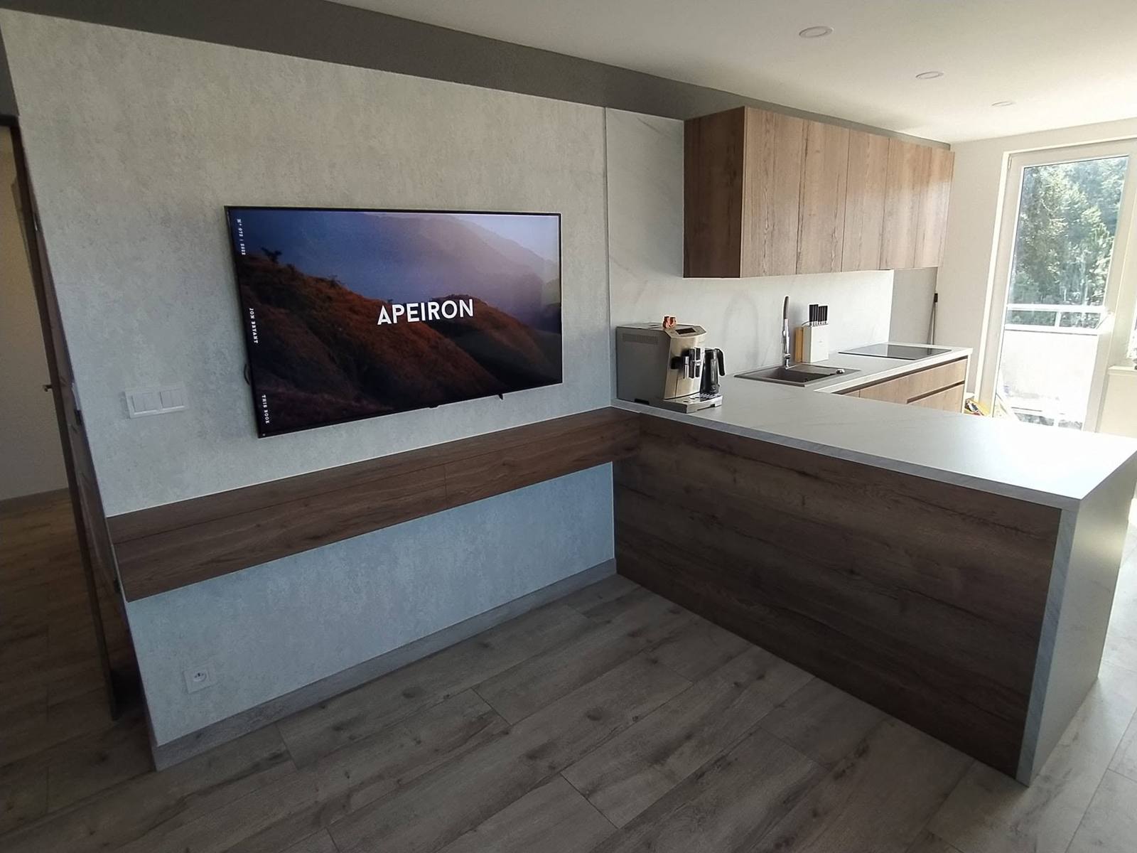 TV-Wand mit Betonpanel und Nussbaumbord neben der Küche