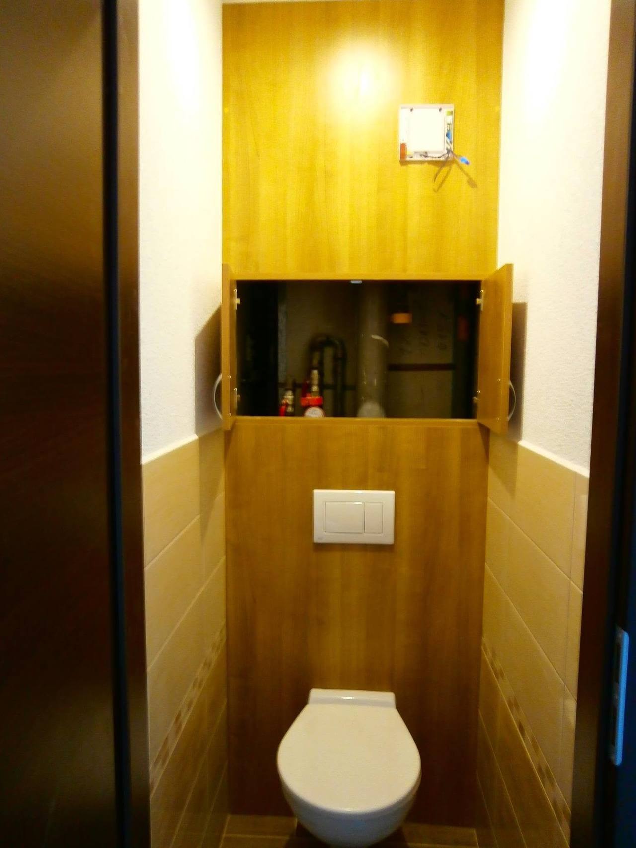 Offener Schrank über dem WC in der mit Holzdekor verkleideten Nische
