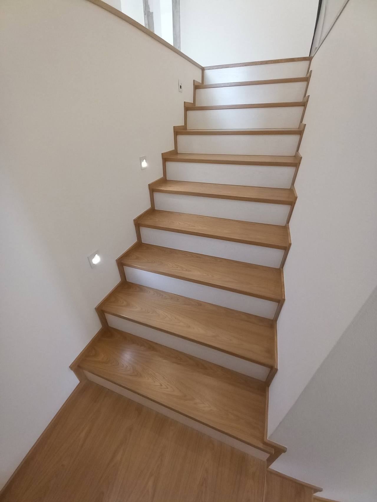 Schmale Eichenstiege mit Spots von unten gesehen