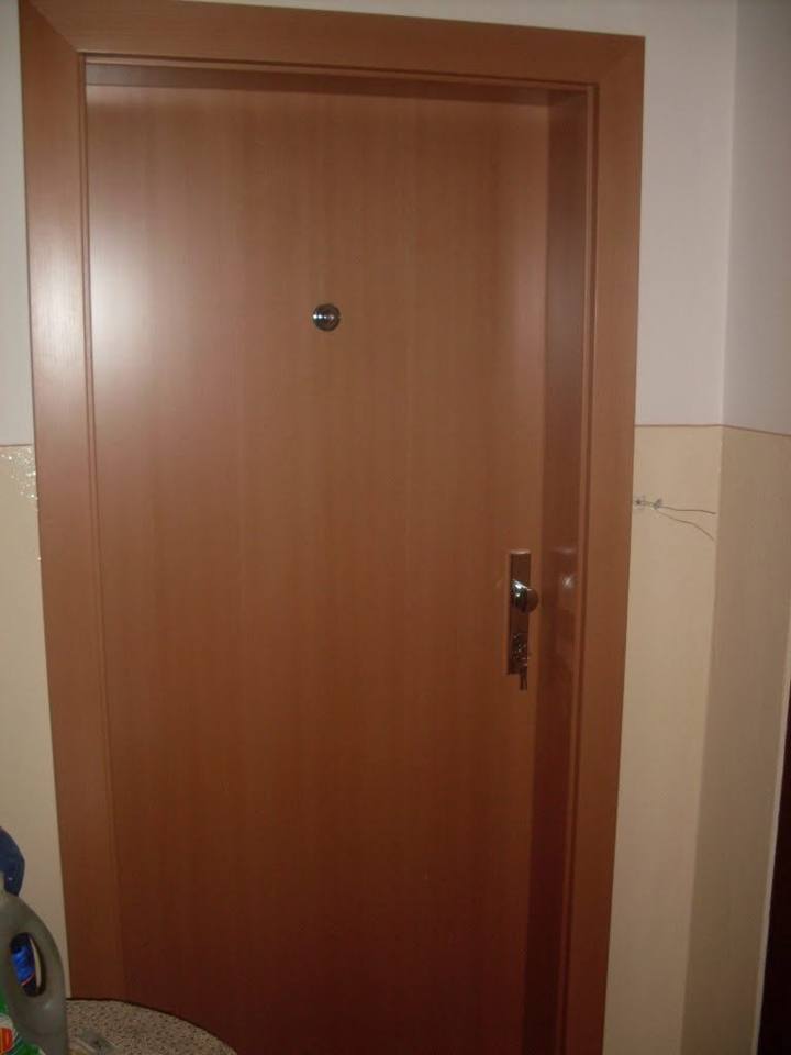 Vchodové dvere bytu v teplom čerešňovom dekore s malým kukátkom.
