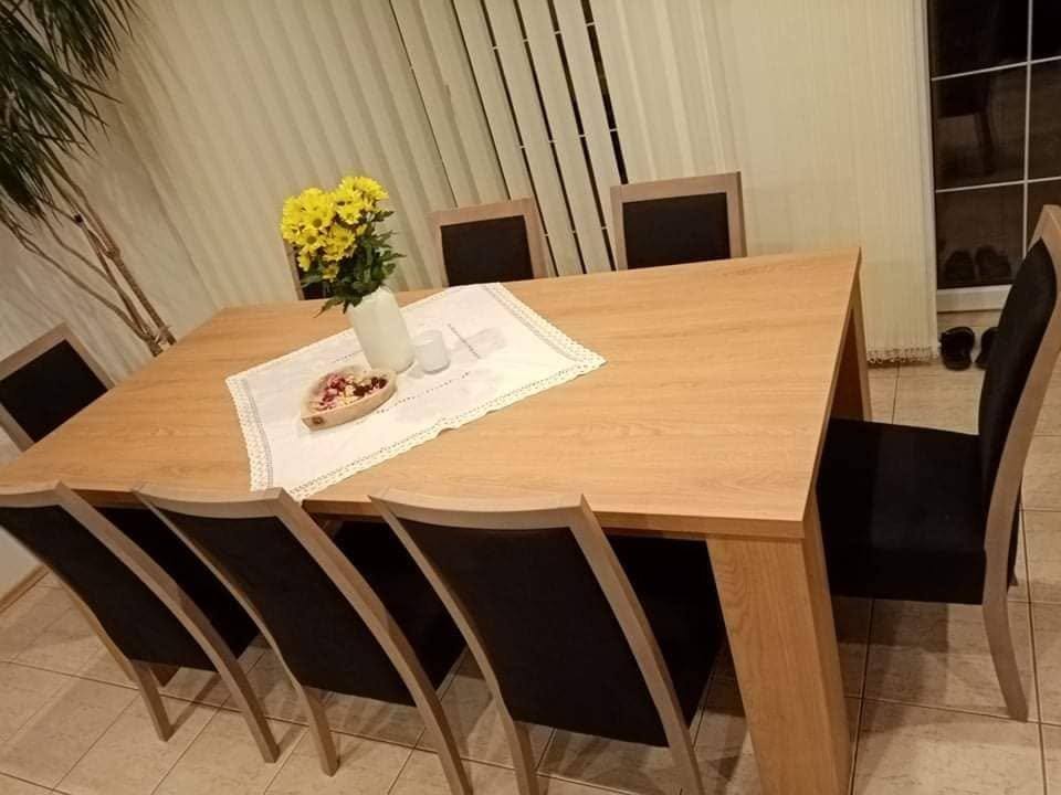 Esstisch in Eichenoptik mit gepolsterten Sesseln und Blumen