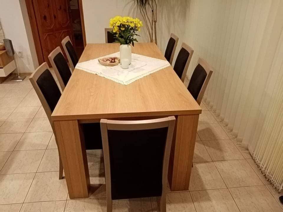 Blick entlang des langen Esstisches mit schwarzen Sesseln