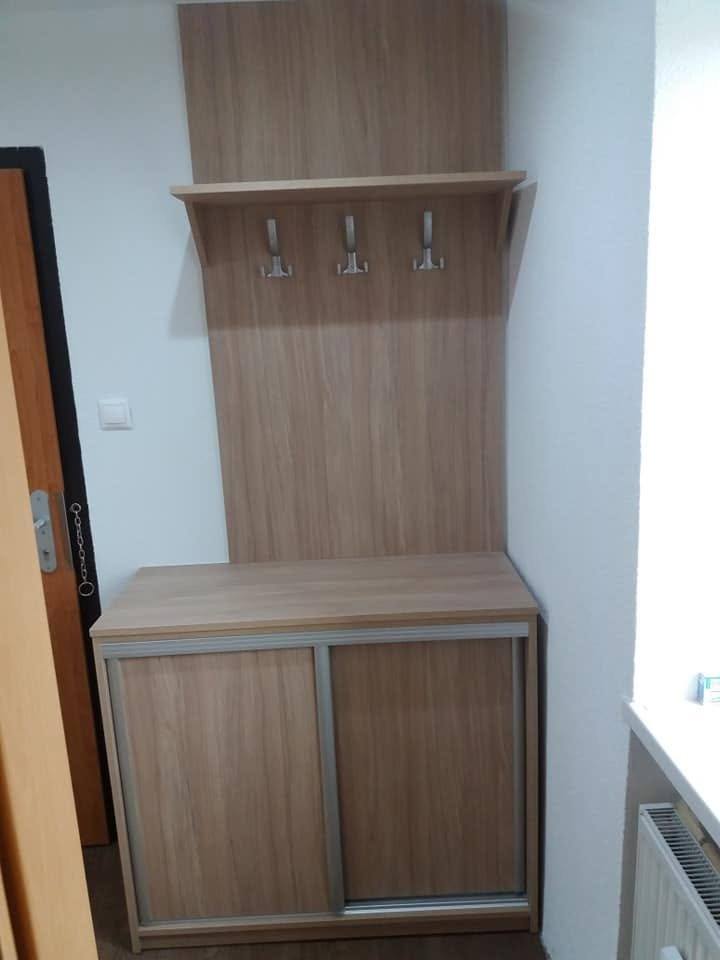 Garderobenboard mit drei Haken über einem Kästchen mit Schiebetüren in Eichendekor.