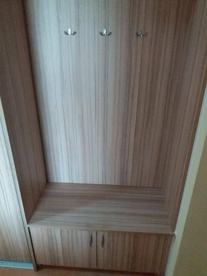 Garderobenpaneel mit drei Haken über einer Sitzbank mit zwei Laden in dunklerem Dekor.